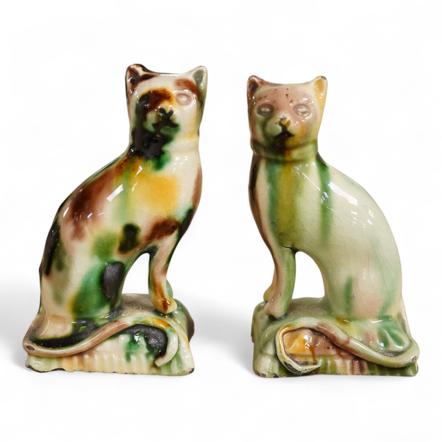 A pair of tortoiseshell glazed pottery figures of cats, early 19th century, 19cm high